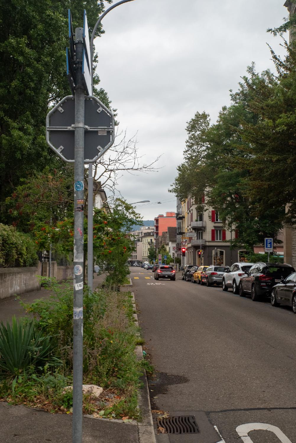A two way city street with 4-5-stories buildings. A car is stopped at a red light.