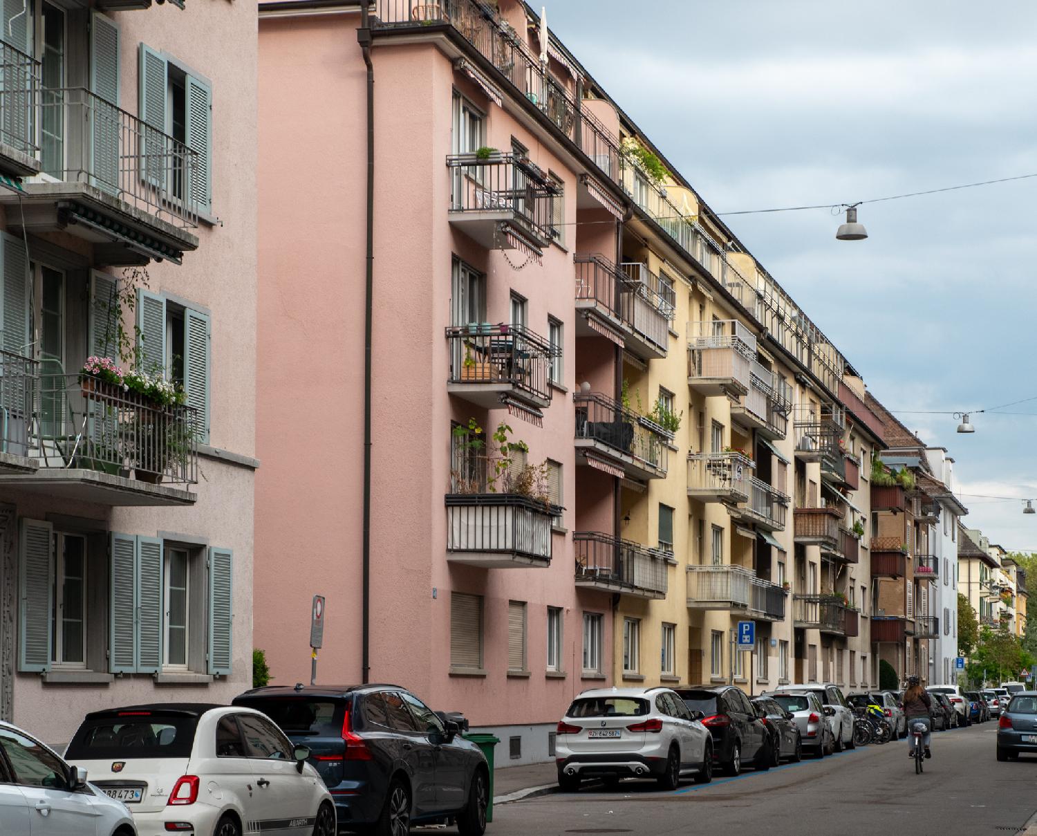 Colorful facades on a street where cars are parked.
