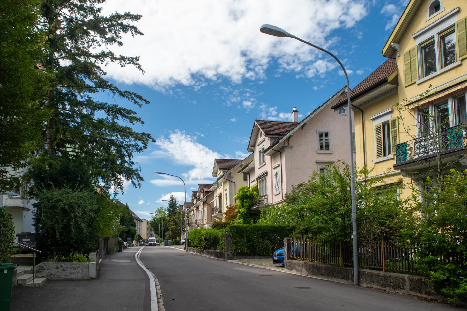 A row of similar-looking (but different color-painted) 3-storey houses in a residential street.