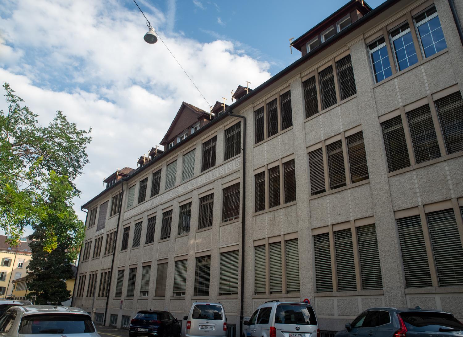 A 4-storey beige/brown office building with a lot of windows and a frieze with square spirals between the 2nd and 3rd floor