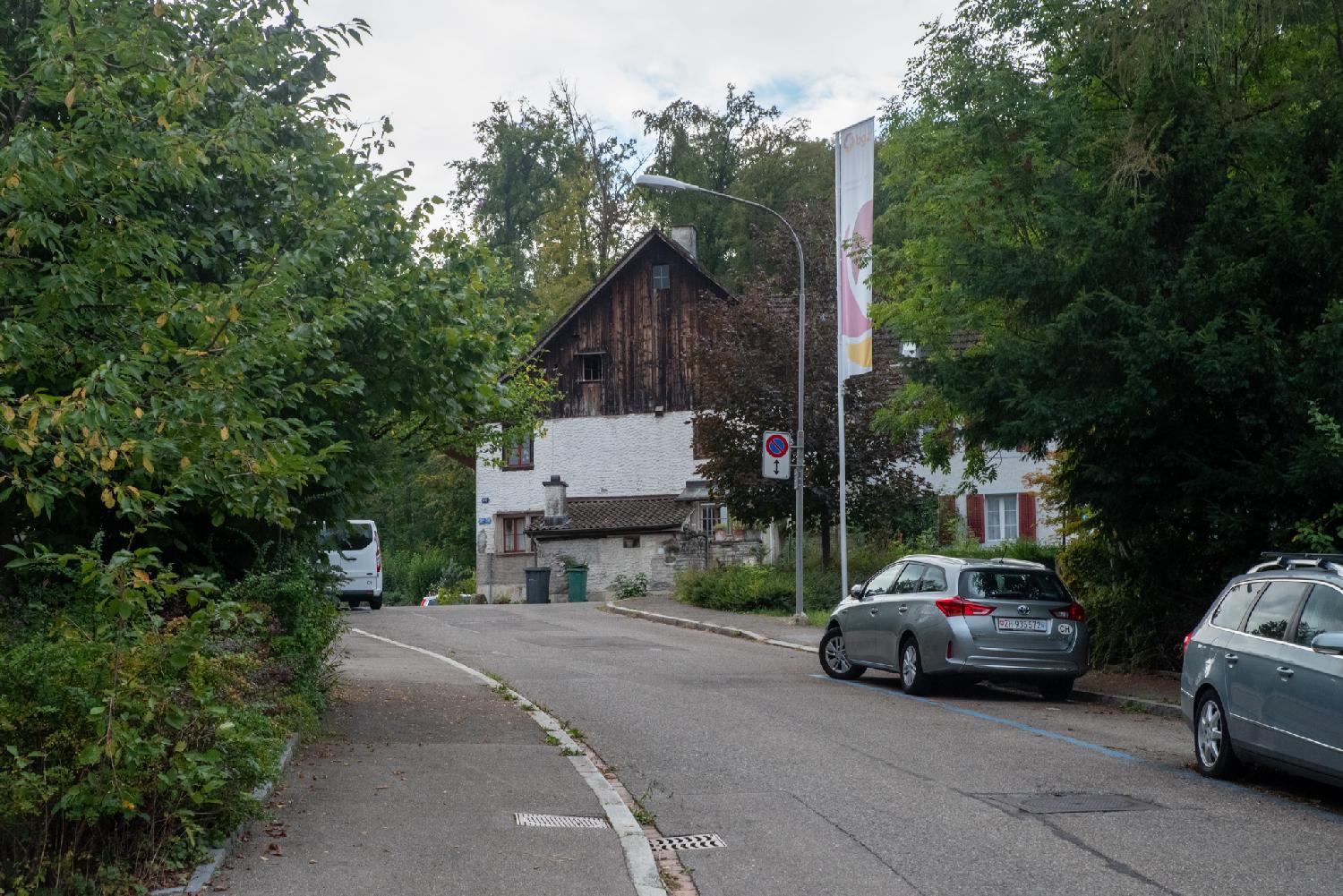 A curved road ending on a house whose second floor is made of dark wood.