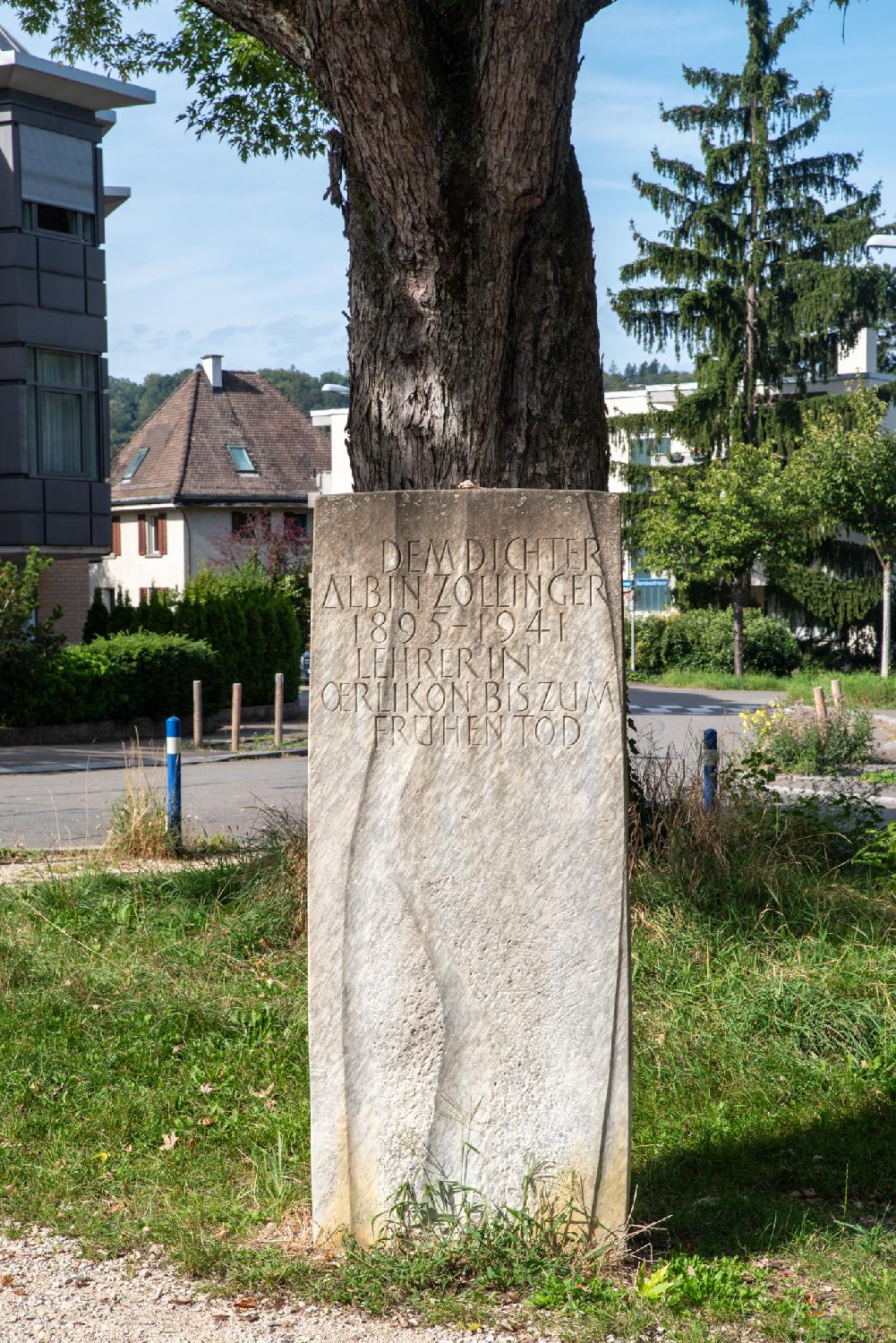 A vertical, ~1.50m stone in front of a tree, reading "Dem dichter Albin Zollinger - 1895-1941 - Lehrer in Oerlikon bis zum frühen Tod".