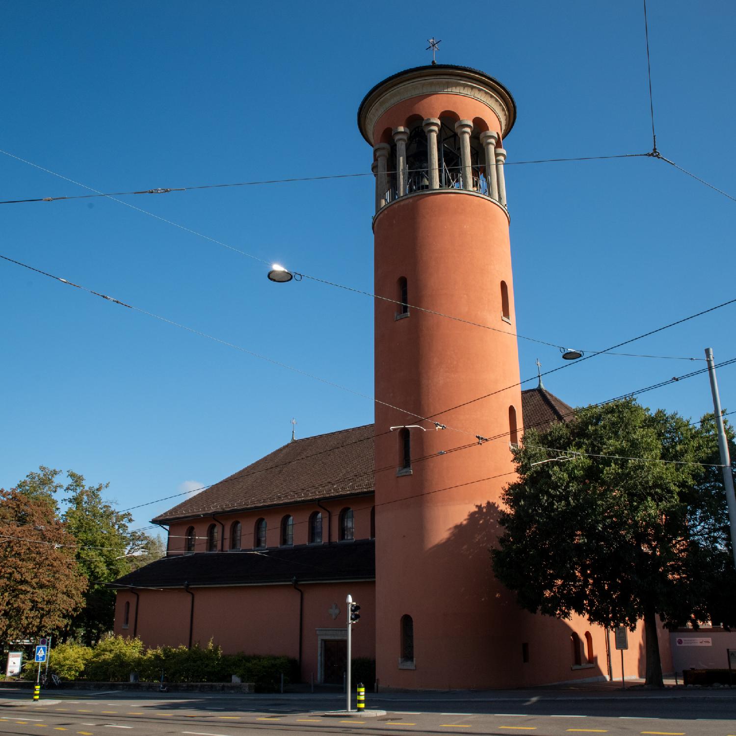 A brick-red church with a round bell tower