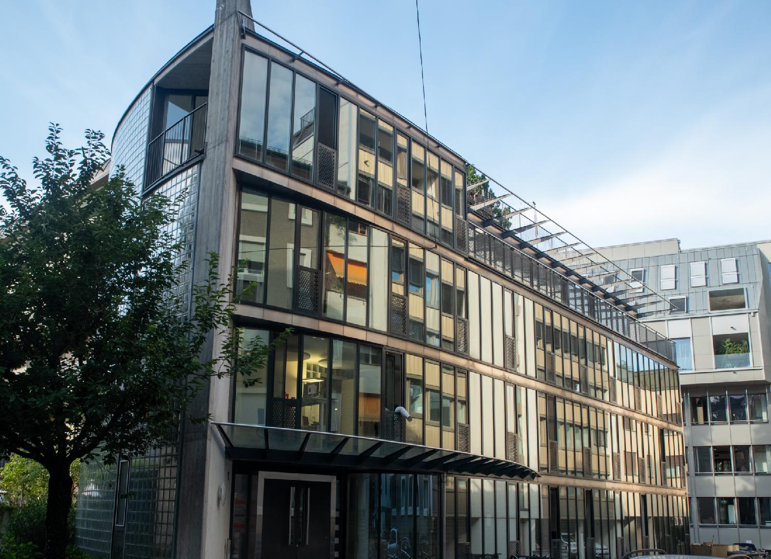 Alte Feldeggstrasse in Zürich: a 4-story building with a lot of windows and a bit of a curve reflecting the brown buildings in front of i
