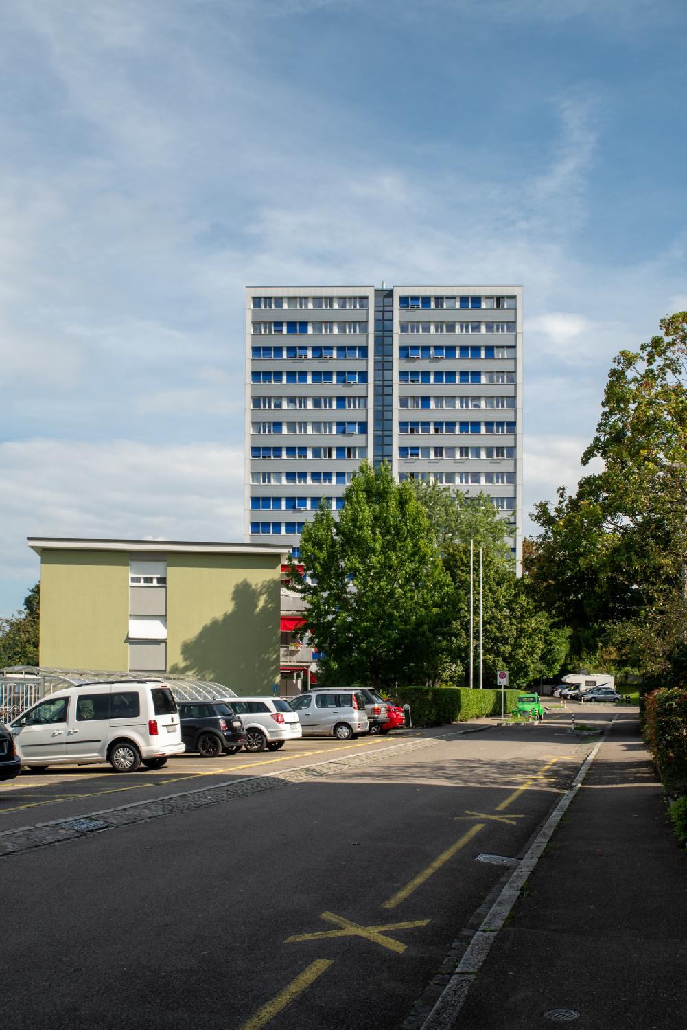 Zürich Alfred-Strebel-Weg. A short dead-end street with a high-rise residential building in the background and cars parked on the right.