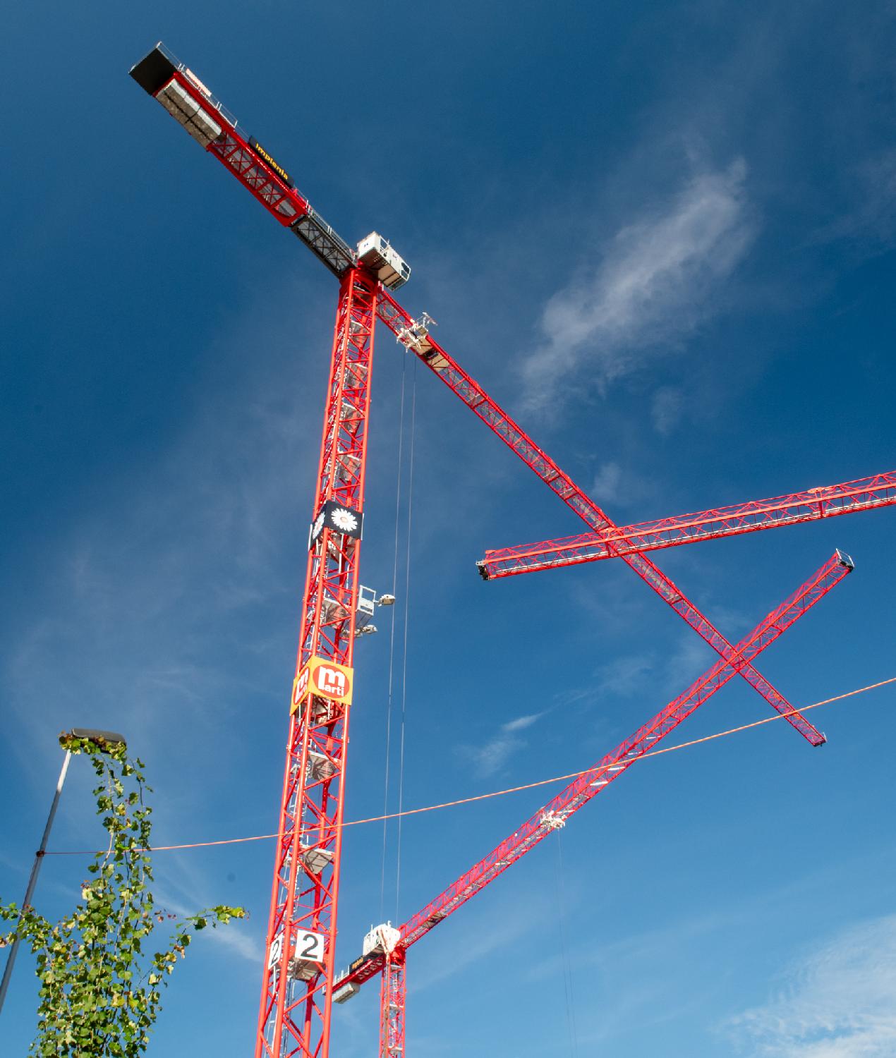 Red cranes forming a triangle in front of the blue sky