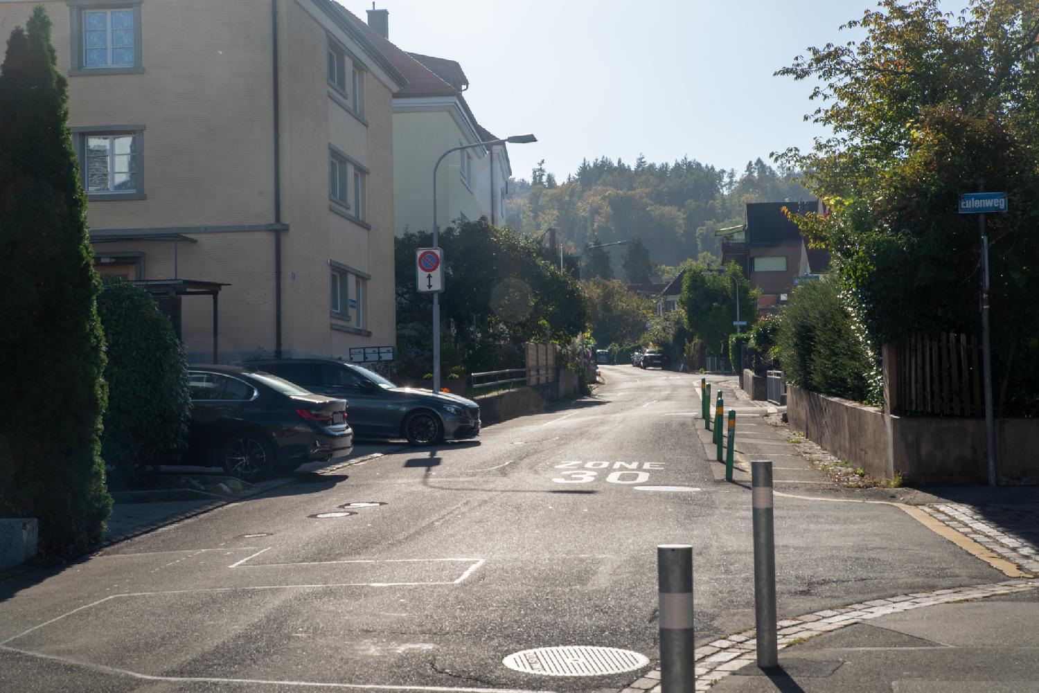 Algierstrasse, a narrow residential road with 3-4-story buildings and trees in the background.