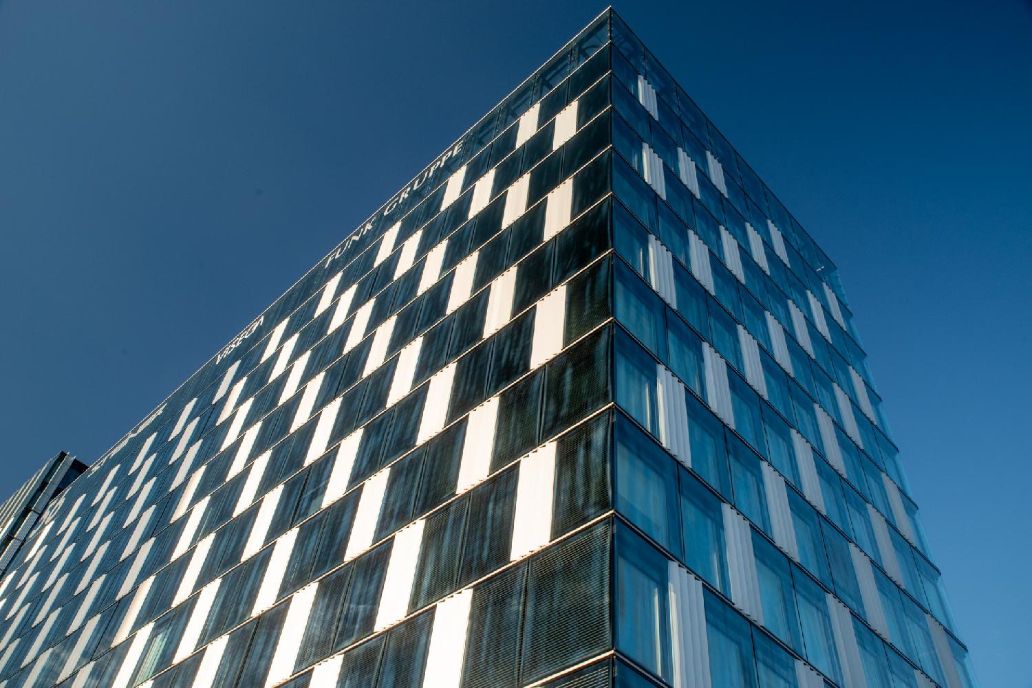 A high rise covered with white surfaces and dark glass panes in a loose checkerboard pattern.