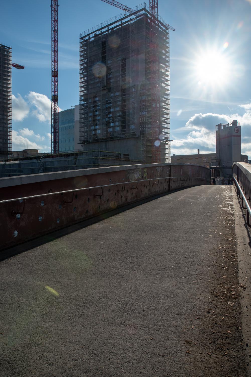 A pedestrian bridge with a couple of high rises in construction on the side of it.