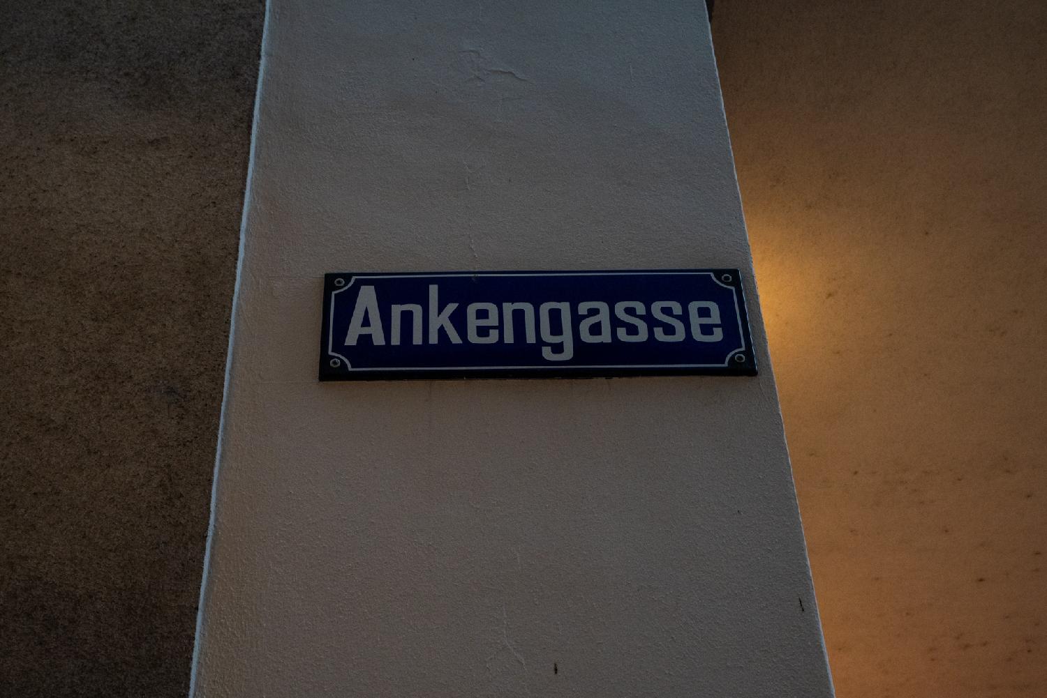 A blue "Ankengasse" street sign on a white wall.