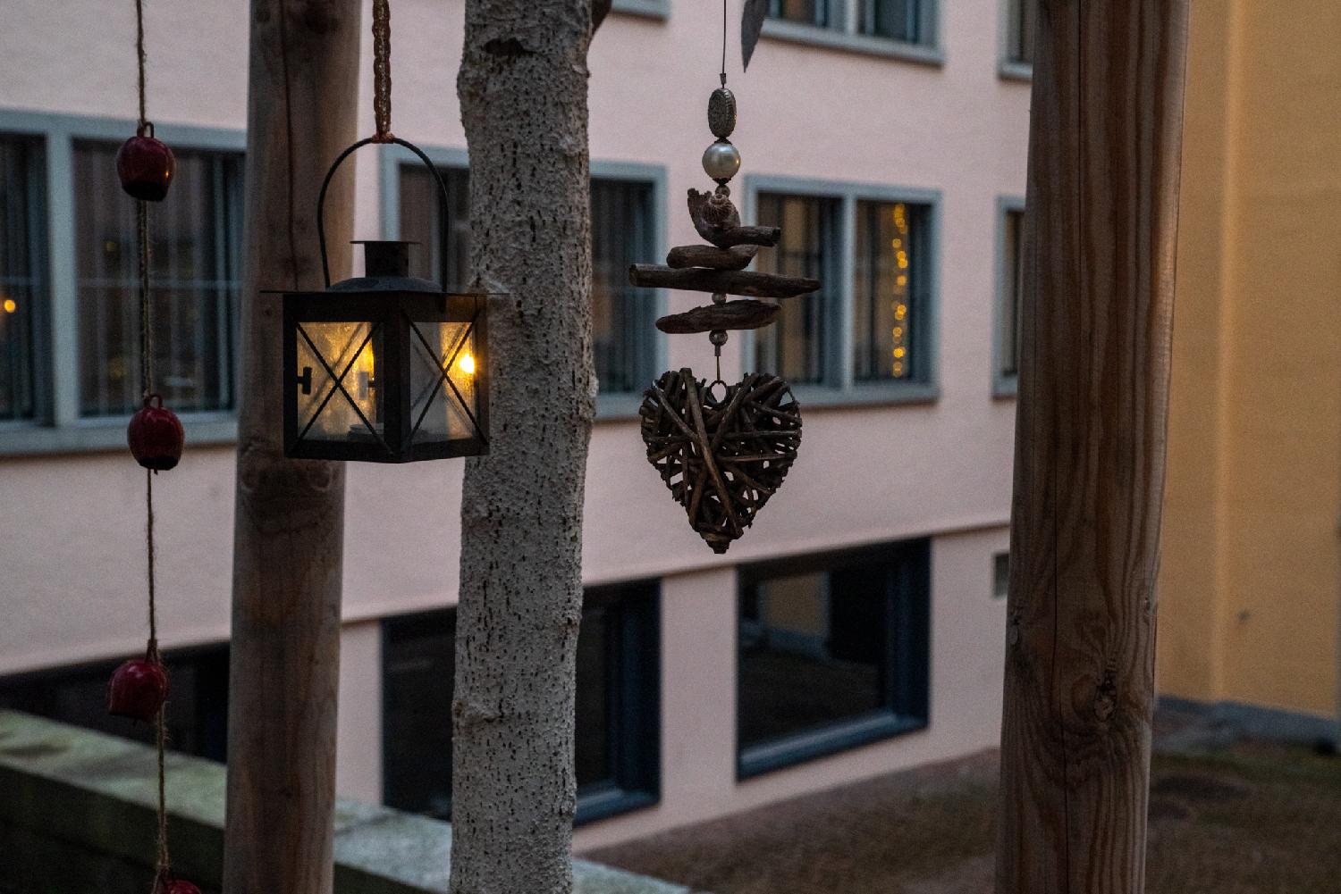 A narrow paved alley between 5-6 storey buildings. A decorated shop hanging sign is visible in the end of the street.