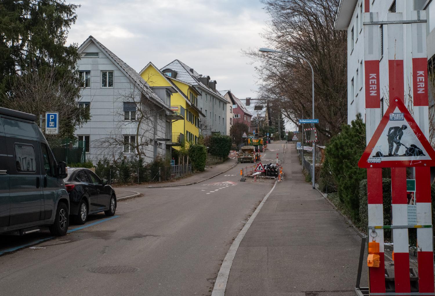A street with 3-story buildings with gable roofs and some road works