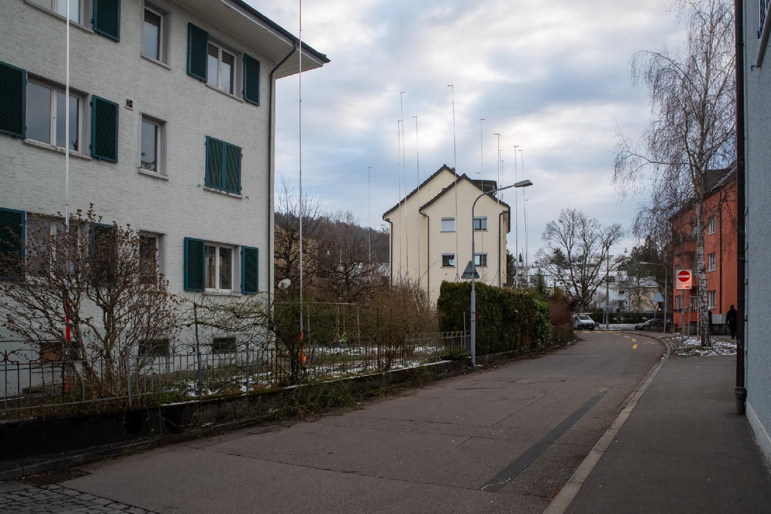 A curved street with a few 3-4 story buildings and construction profiles showing the height of a future building