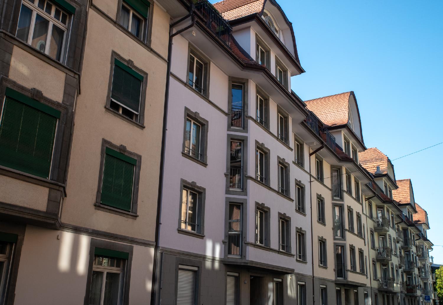 Facades of 5-story buildings with protruding windows and dormer windows under arched roofs.