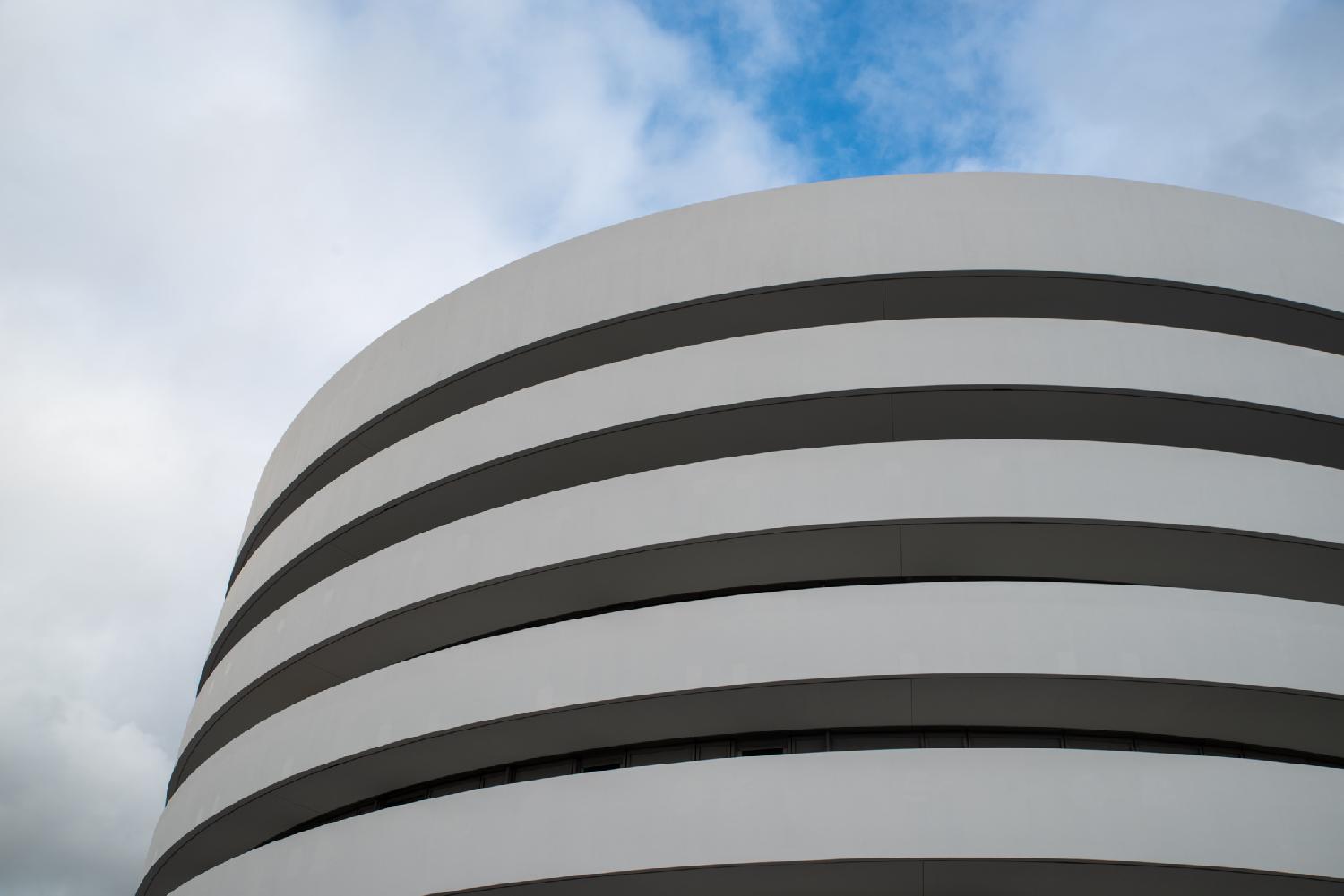 A round building with white balconies covering recessed windows.