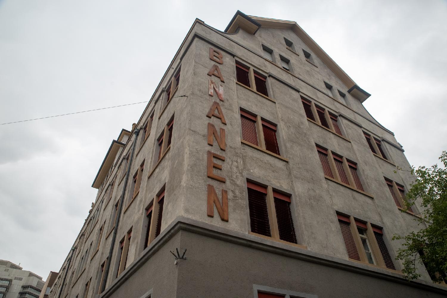 A grey/brown concrete building with "Bananen" written vertically in large letters on the side