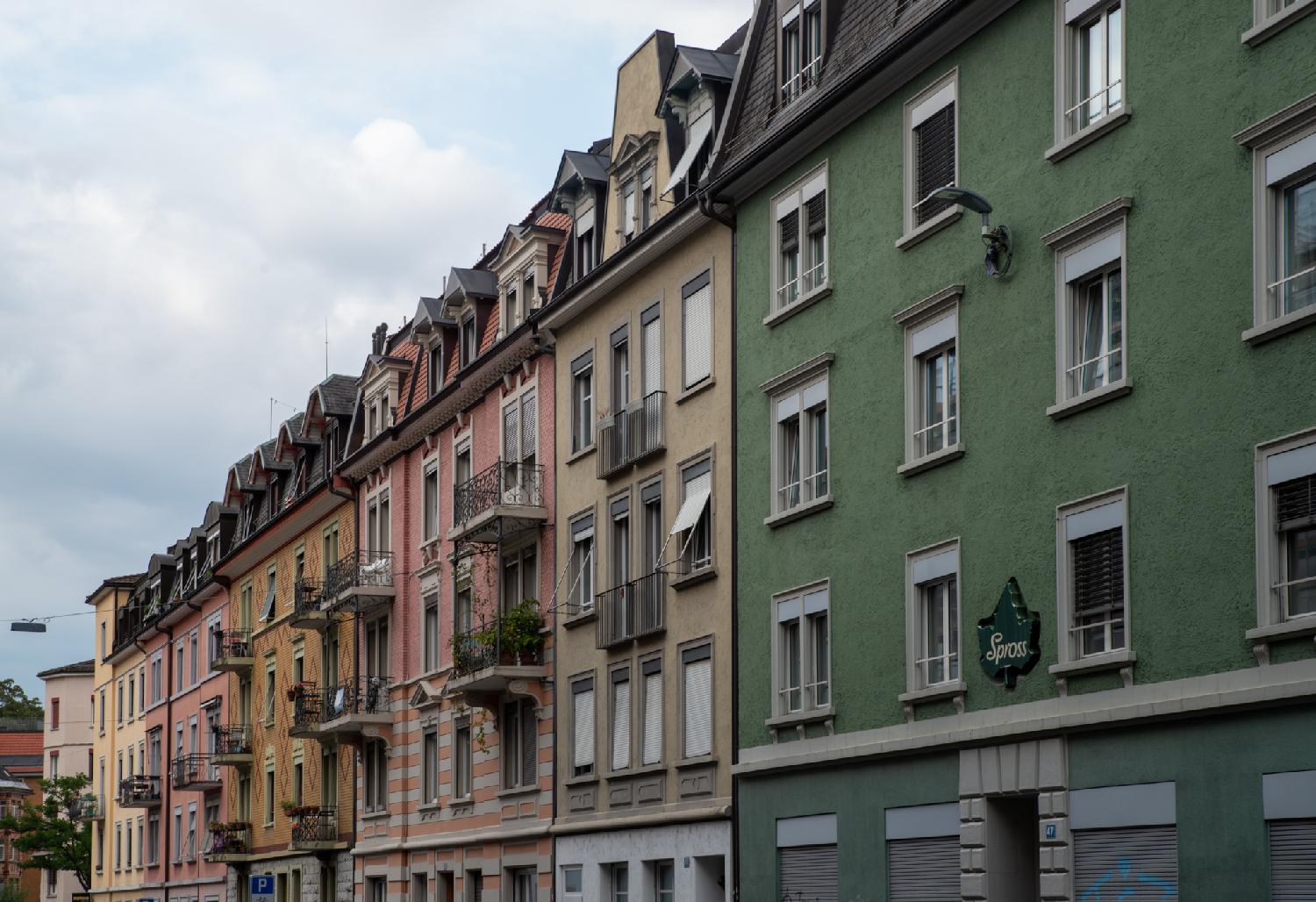 Colorful (yellow, pink, green) façades of 4-storey buildings with dormer windows on top