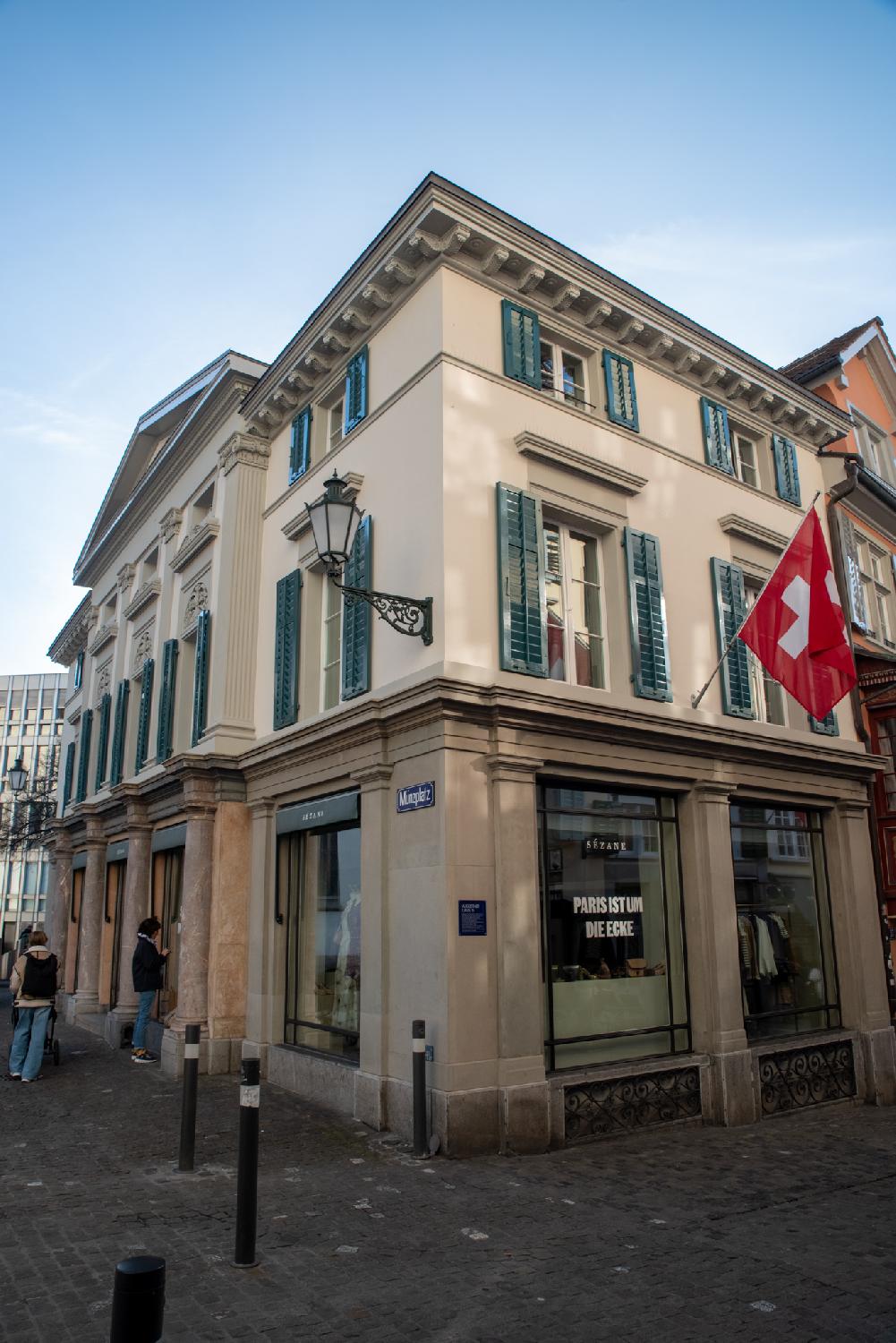 A building on a street corner, with the entrance façade showing columns and a framed gable roof.