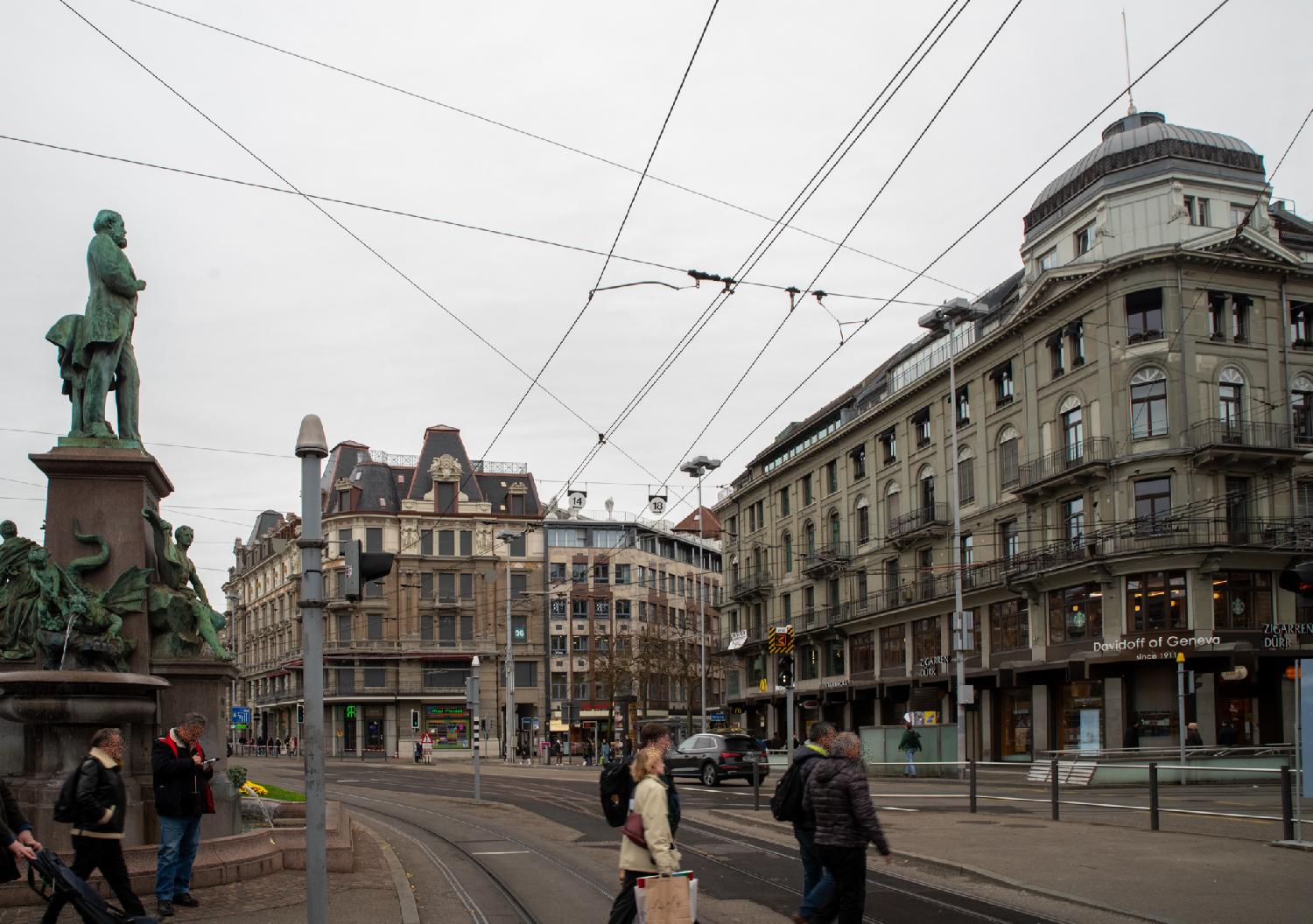 A large square with multiple roads, two tram railtracks, and 5-6-story buildings around the square. A fountain/statue is visible in the left side of the picture.